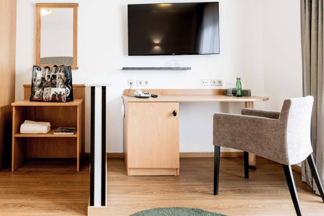 Blick auf Schreibtisch Smart TV und Minikühlschrank