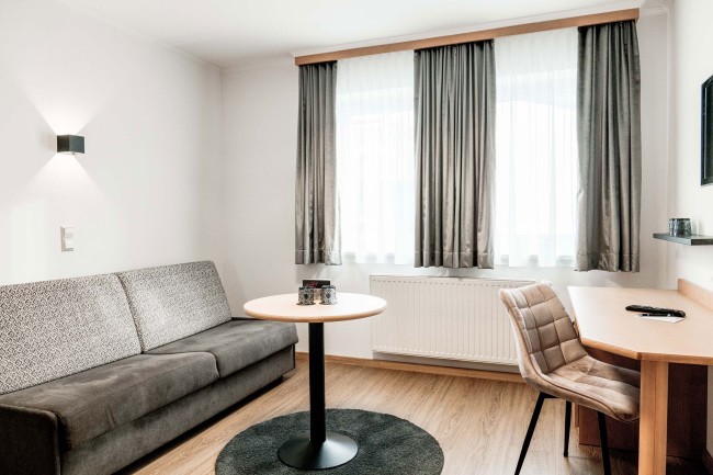 Blick von Wohnraum mit Couch auf Schlafzimmer mit Doppelbett