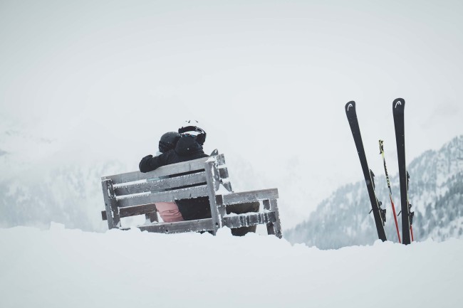 Personen sitzen auf einer Bank in einer Winterlandschaft